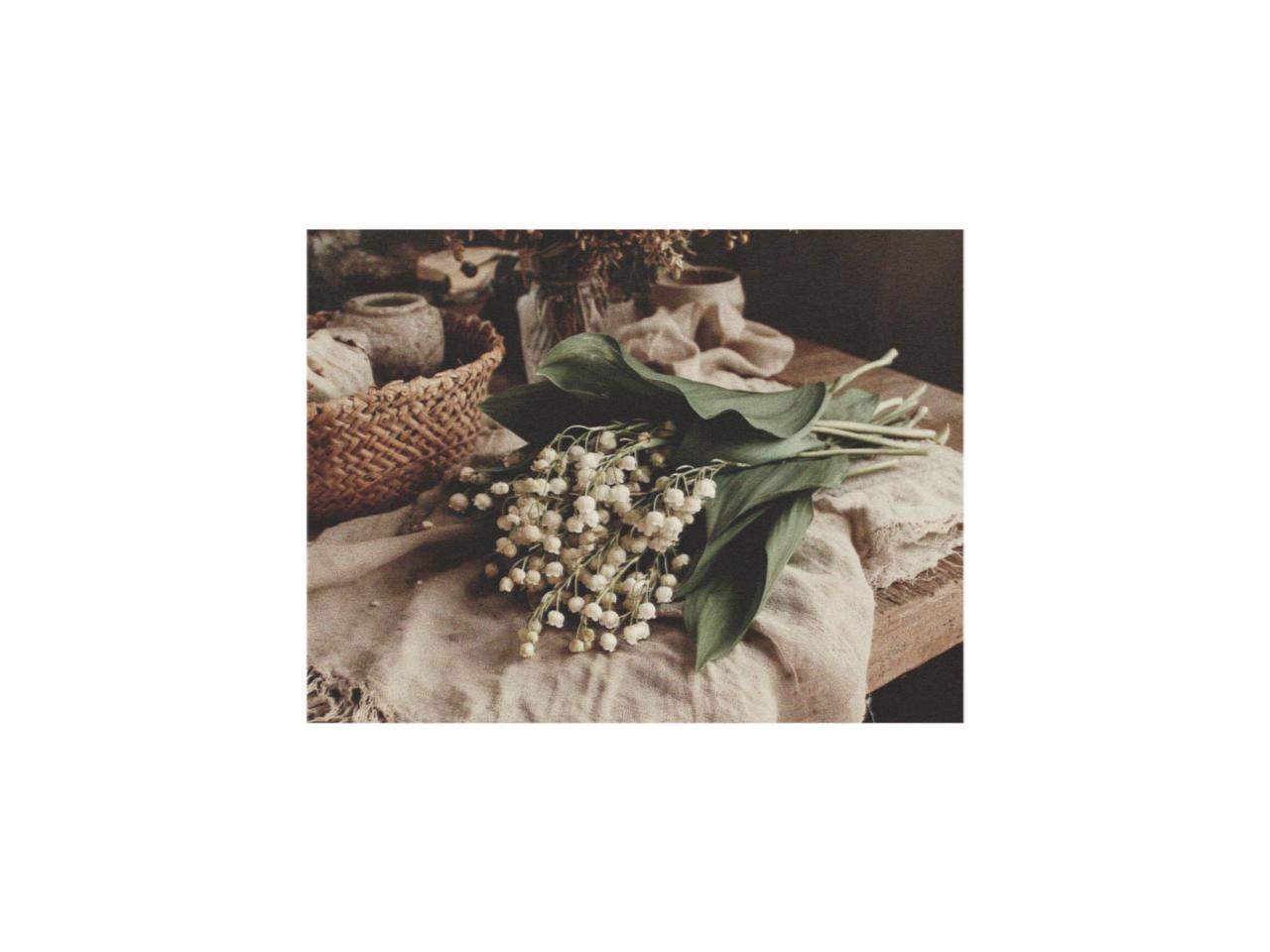 lily of the valley gifts arranged on linen fabric over a rustic wooden table in a warm natural still life scene.